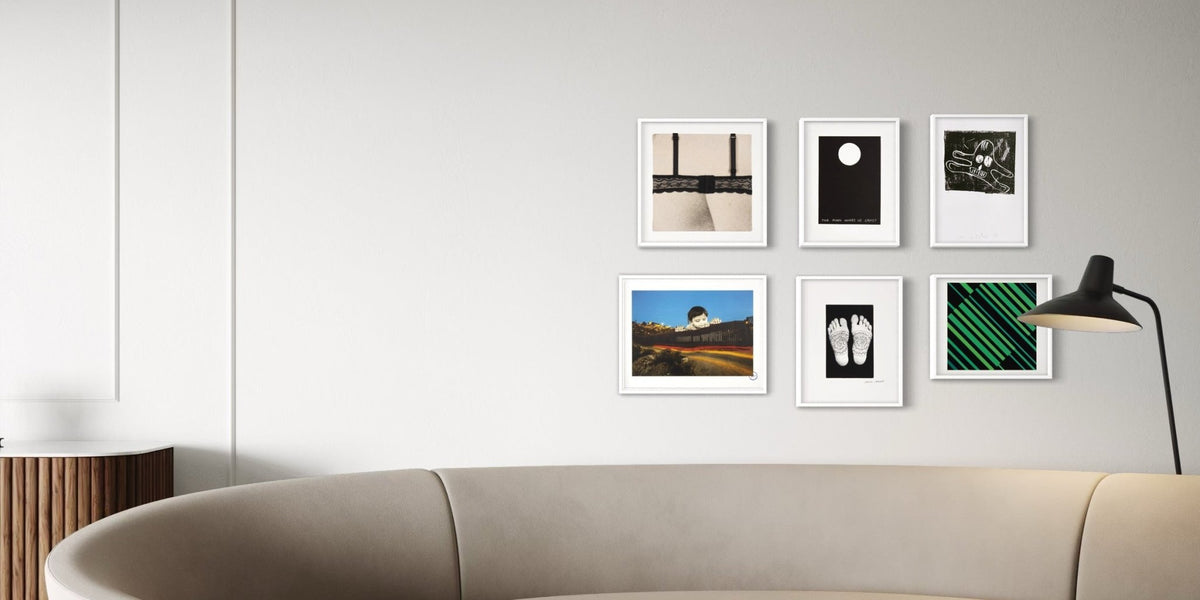 Start an art collection with a contemporary wall display of framed artworks above a sofa in a modern interior.