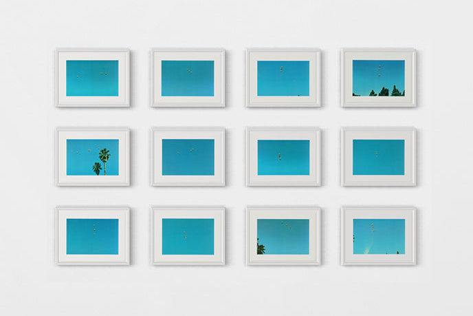 John Baldessari, Throwing Three Balls: Grid of framed blue artworks on a white wall